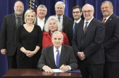 Gov. Mark Dayton signed the unemployment benefits bill Thursday as northern Minnesota lawmakers looked on.