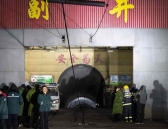 Rescuers and staff members wait outside the site of the coal mine explosion in Pingyao.