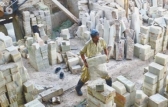 A worker moves masrble blocks to a stone cutting unit.