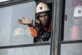 A rescued miner gestures out a bus window carrying some of the hundreds of miners rescued from the Beatrix gold mine shaft.