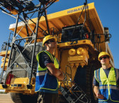 Williams Racing drivers Alex Albon (L) and Franco Colapinto check out two Komatsu 930E before driving them.
