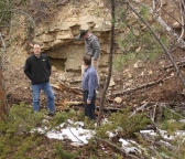 Two of the owners of the Deadwood Standard Project, along with a member of the public, examine an old mine crater and tunnel.