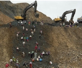 Freelance jade miners collect jade stones in an earth dump of a companies' mining field in Hpakant area. (photo: AP)