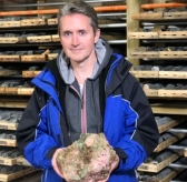 Trent Mell, chief executive of First Cobalt, holds a sample of the metal in a northern Ontario shed. (photo: Carly Thomas, CBC)